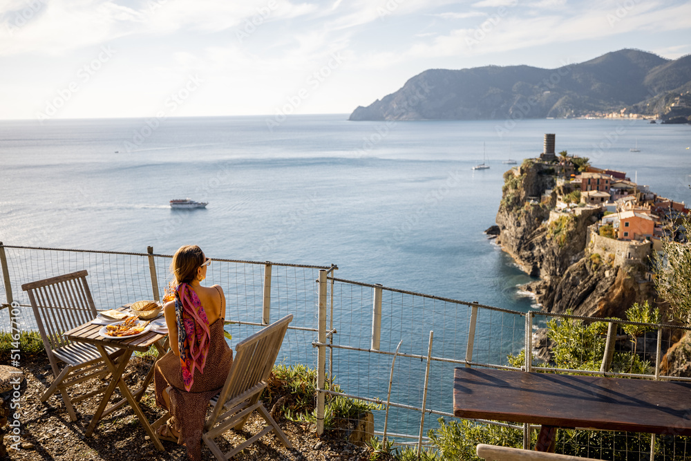 Woman sitting at outdoor restaurant with beautiful landscape of coastline in Vernazza, traveling in 