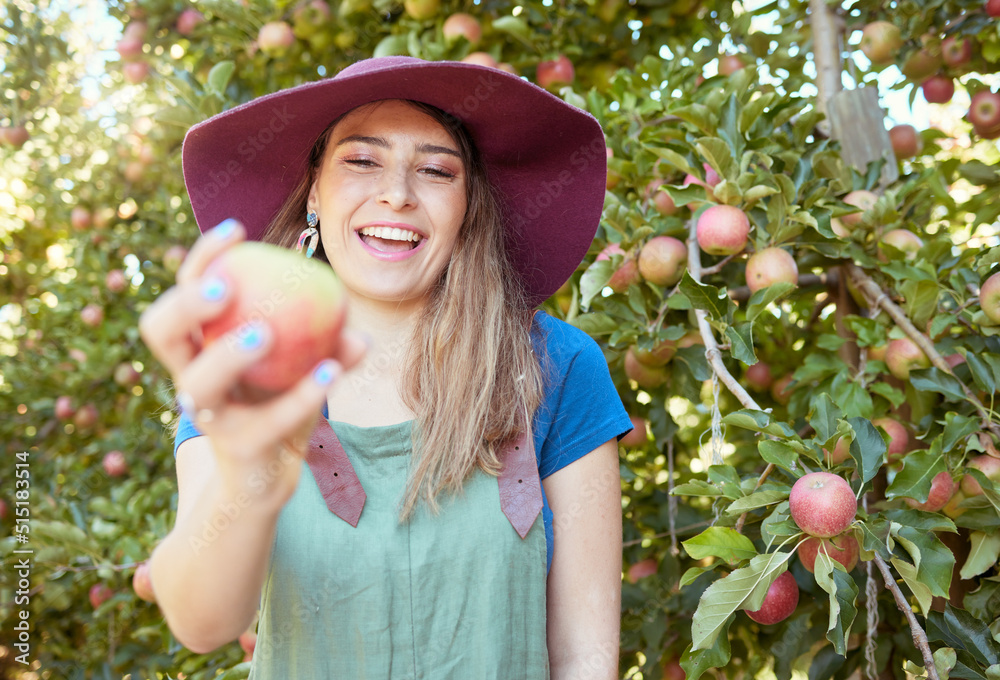 Beautiful young woman holding an apple on a farm. Happy lady picking apples in an orchard. Fresh fru