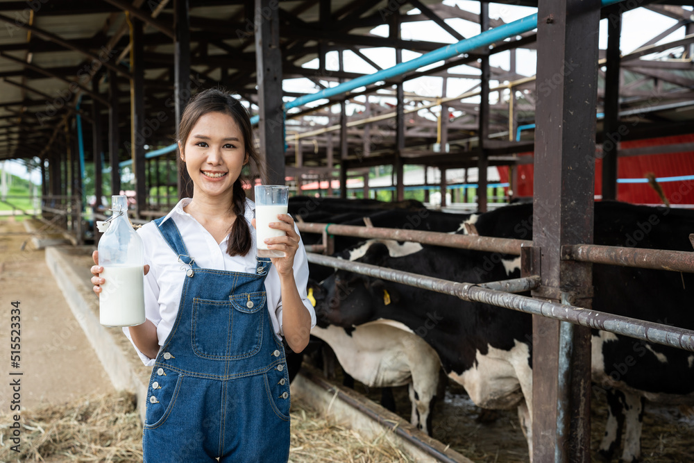 亚洲女奶农在牛棚里拿着一瓶牛奶的画像