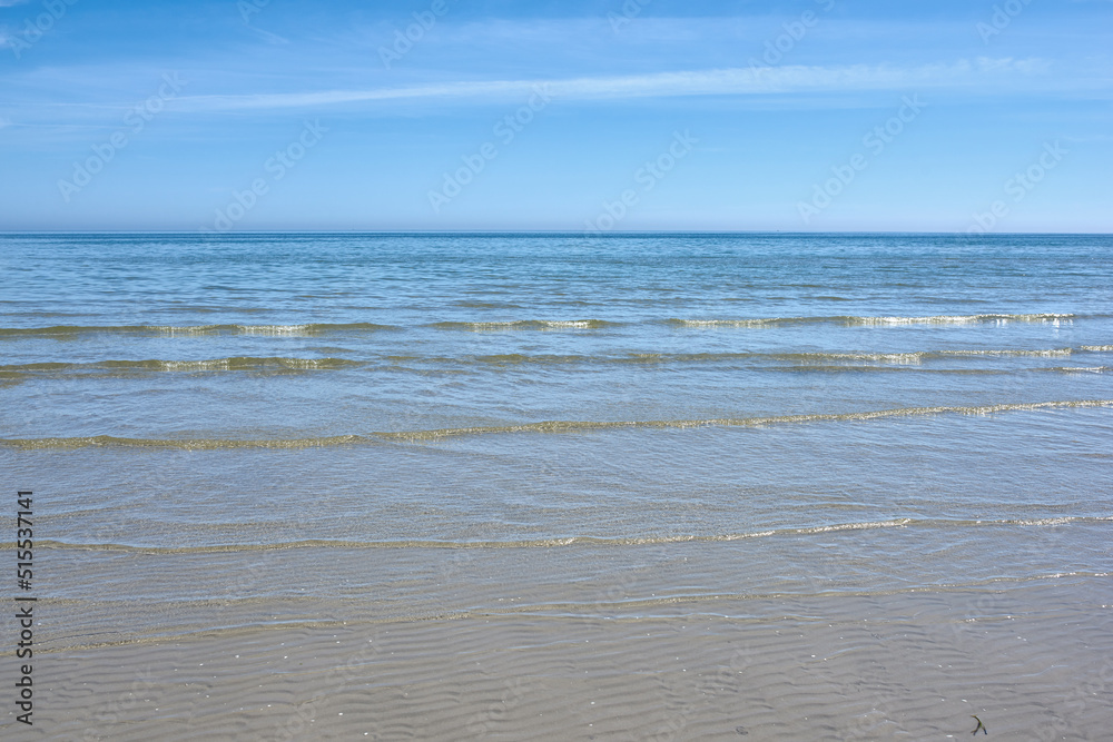 岸边的小海浪映衬着晴朗的蓝天，有复制空间。开阔的风景