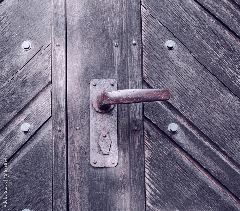 一扇奇怪的旧木门，门把手生锈。一个老式的门把手。一个传统的特写
