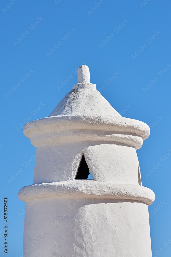 在晴朗的蓝天背景下，在房屋或建筑物的屋顶上设计的白色烟囱或钟楼