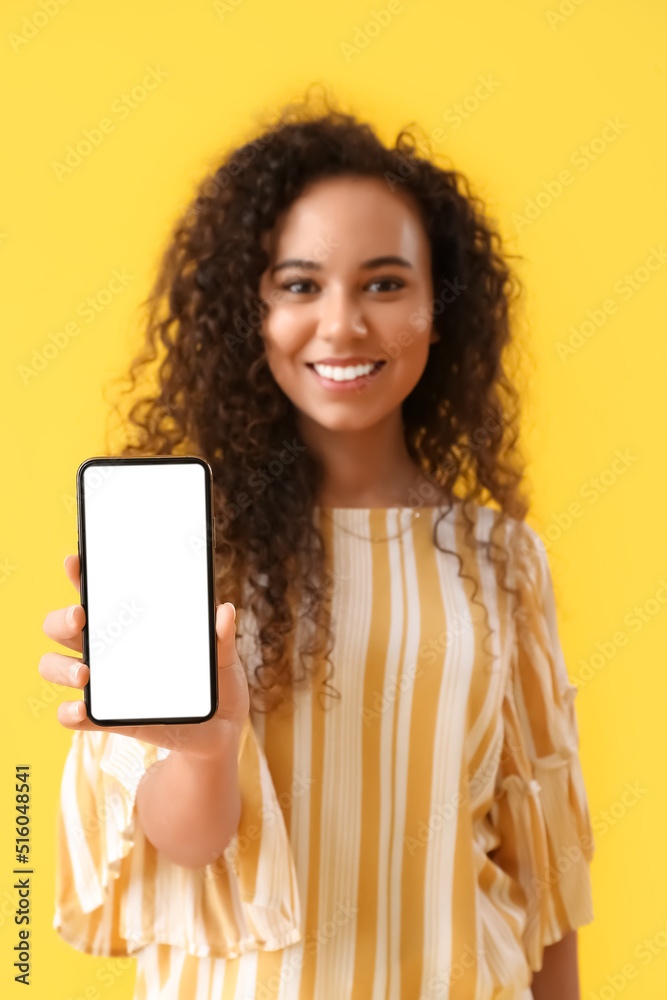 黄色背景下拿着手机的年轻非裔美国女性