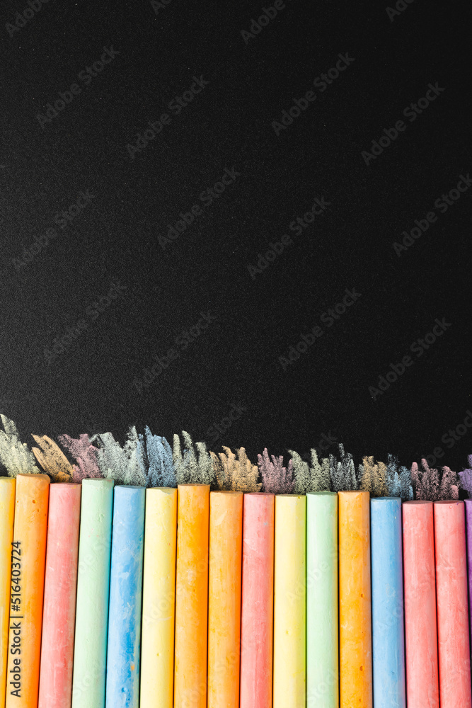 Vertical composition of colorful pastels on black surface with copy space
