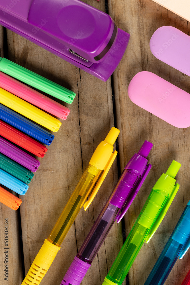 木制表面彩色蜡笔、钢笔、马克笔和其他学习工具的垂直构图