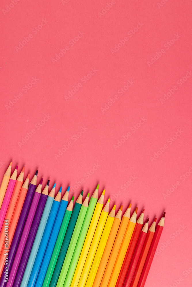 彩色蜡笔在粉红色表面的垂直构图，带有复制空间