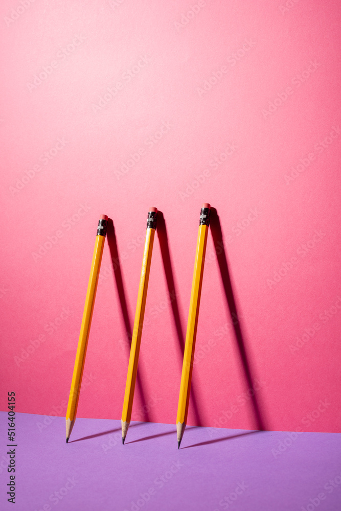 粉色和紫色背景上一排铅笔的垂直构图