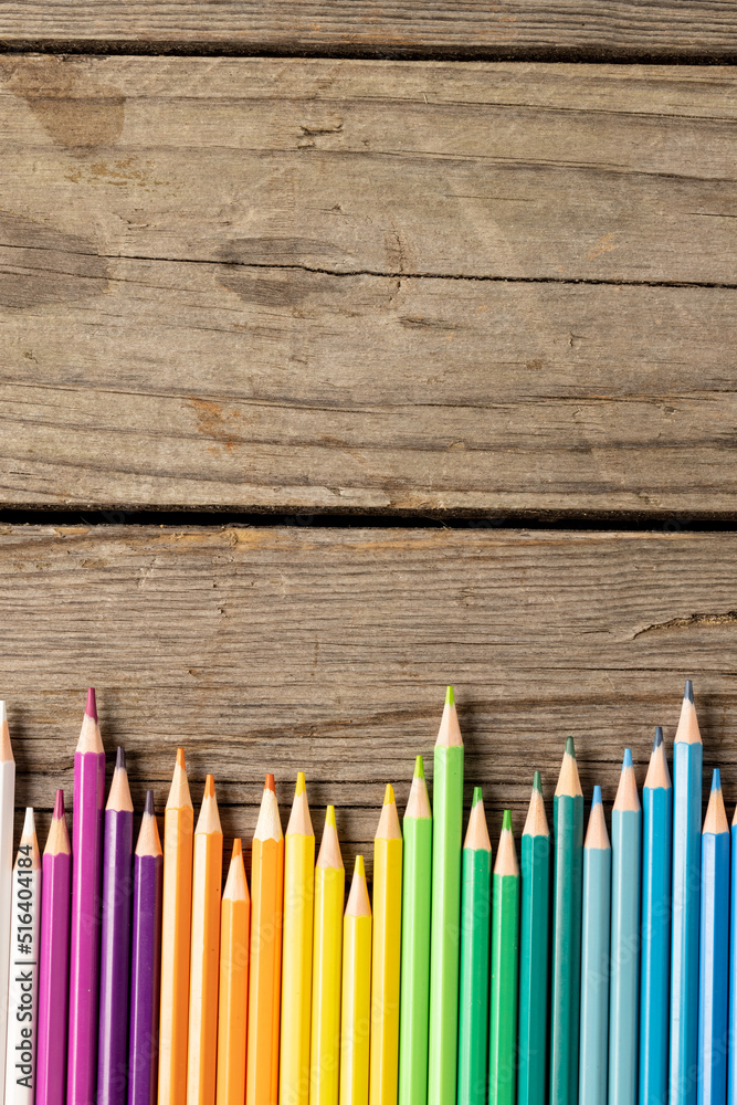 Vertical composition of colorful crayons on wooden background