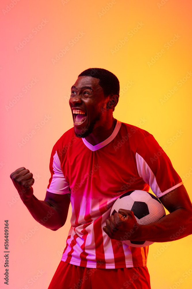 快乐的非洲裔美国男子足球运动员，在霓虹灯下踢足球