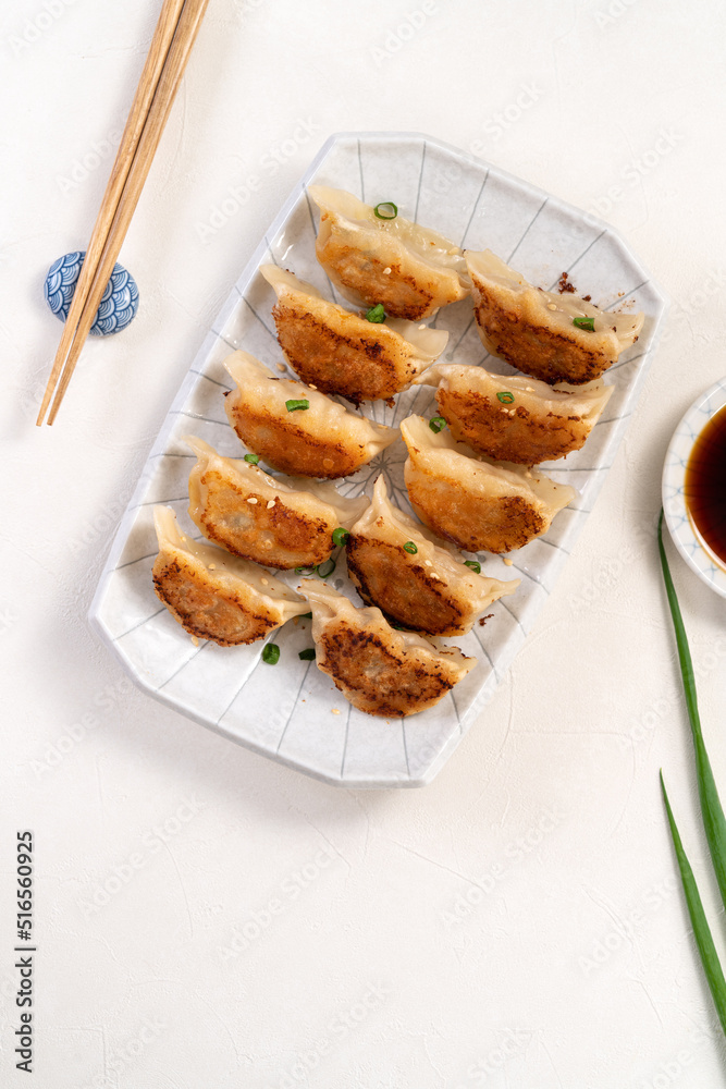 用酱油在白色桌子背景上的盘子里煎饺子饺子饺子。