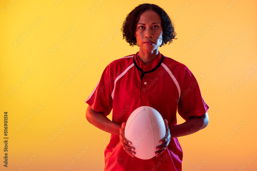手持霓虹黄灯橄榄球的非裔美国女橄榄球运动员的肖像