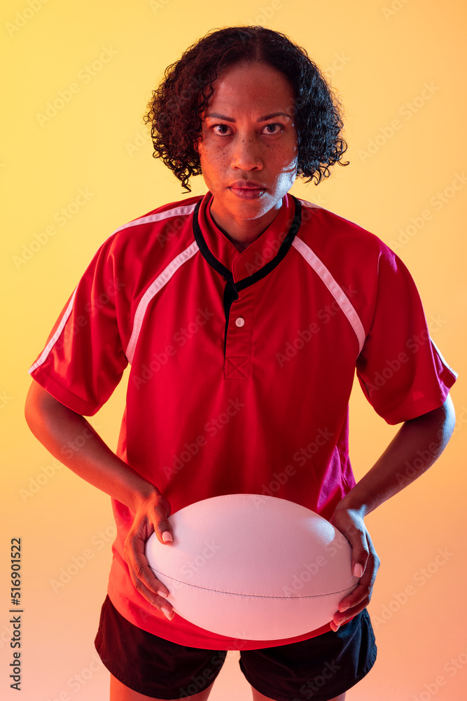 霓虹黄灯下拿着橄榄球的非裔美国女橄榄球运动员的肖像