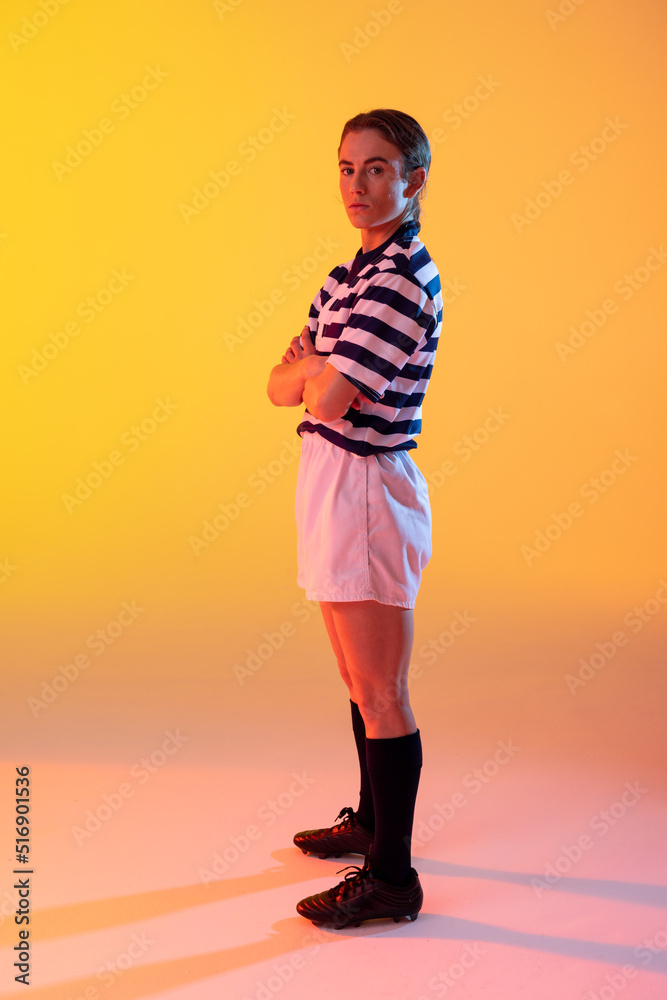 高加索女子橄榄球运动员的肖像，双臂交叉在霓虹黄色的灯光下