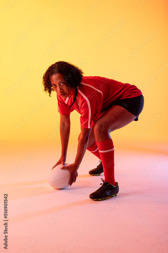 霓虹黄灯下拿着橄榄球的非裔美国女橄榄球运动员的肖像
