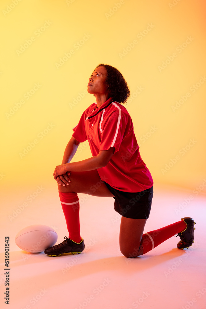 非裔美国女橄榄球运动员在霓虹黄灯下拿着橄榄球