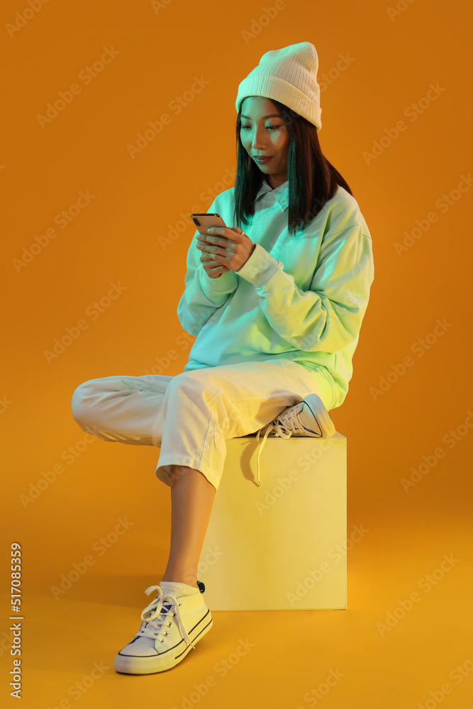 橙色背景智能手机的亚洲女性博主