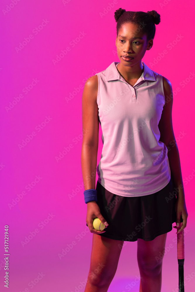 Vertical image of african american female tennis player in violet and pink neon lighting