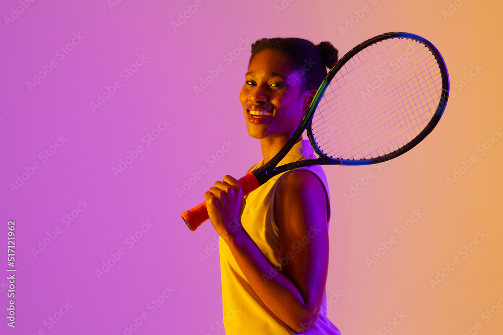 快乐的非裔美国女网球运动员在霓虹灯、紫色和黄色灯光下的形象