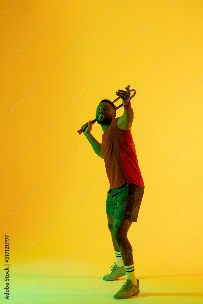 黄色灯光下快乐的非裔美国男子网球运动员的垂直形象