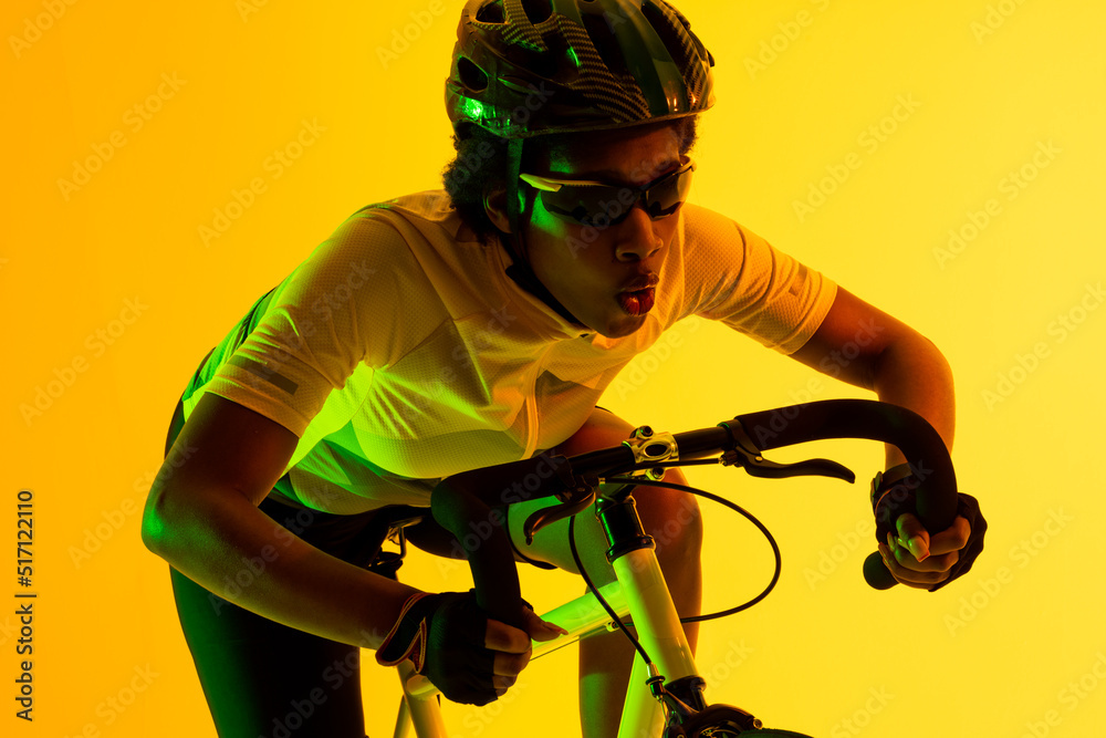 非裔美国女自行车手在黄色灯光下骑自行车的照片