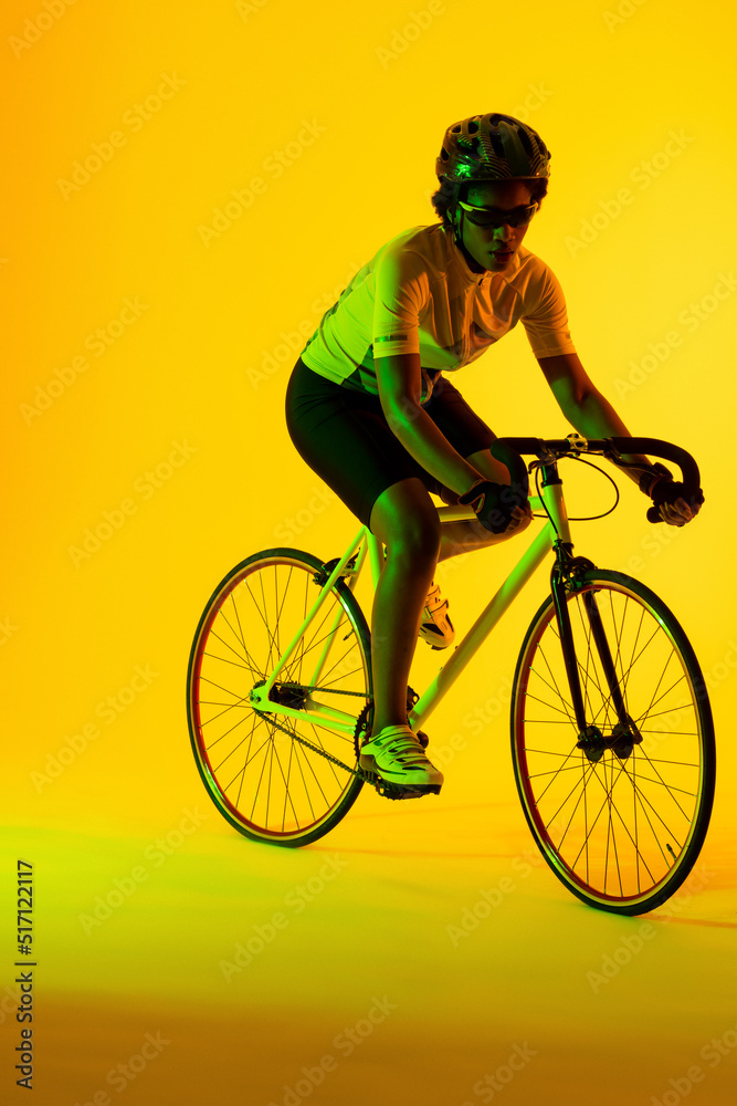 非裔美国女自行车手在黄色灯光下骑自行车的垂直图像