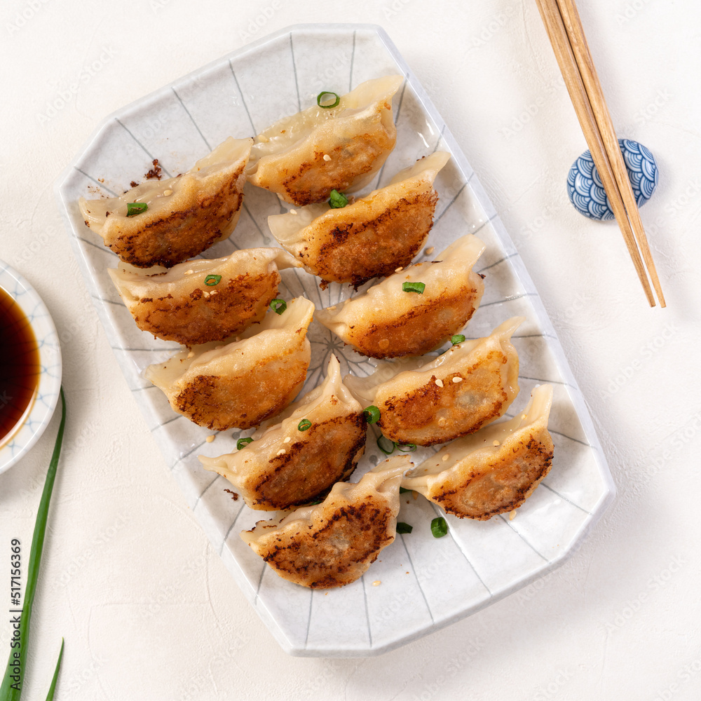白桌子背景上放着酱油的锅里煎饺子饺子饺子。