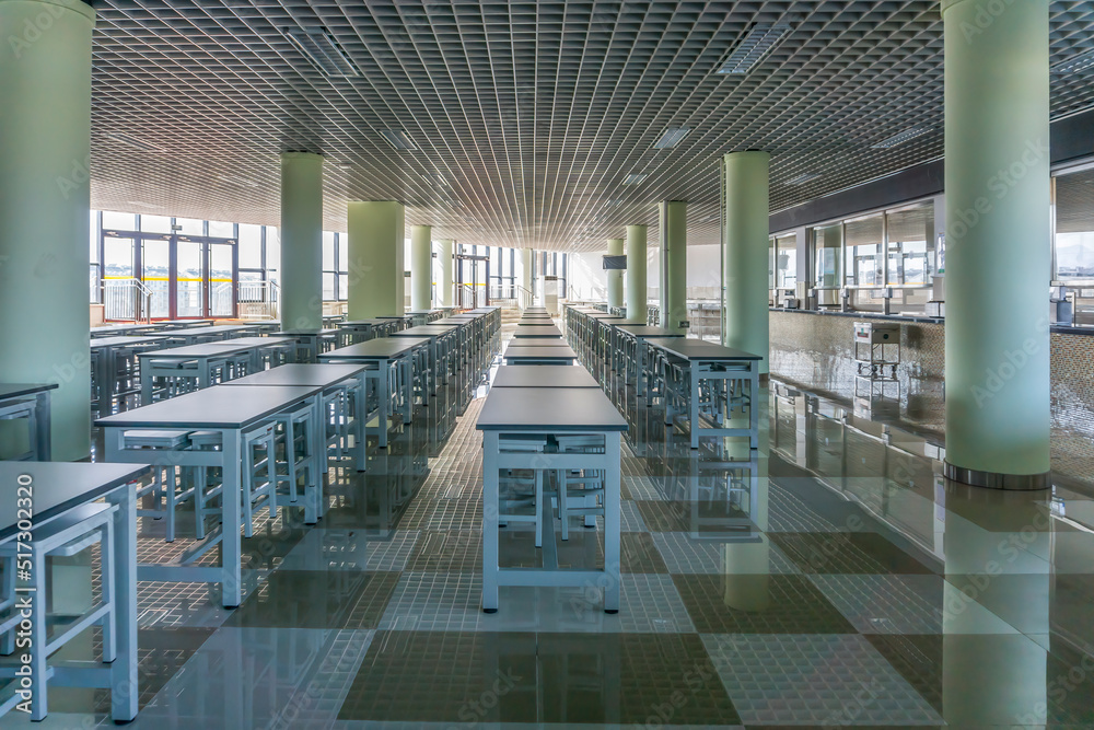 干净的学校自助餐厅，有很多空座位和桌子。