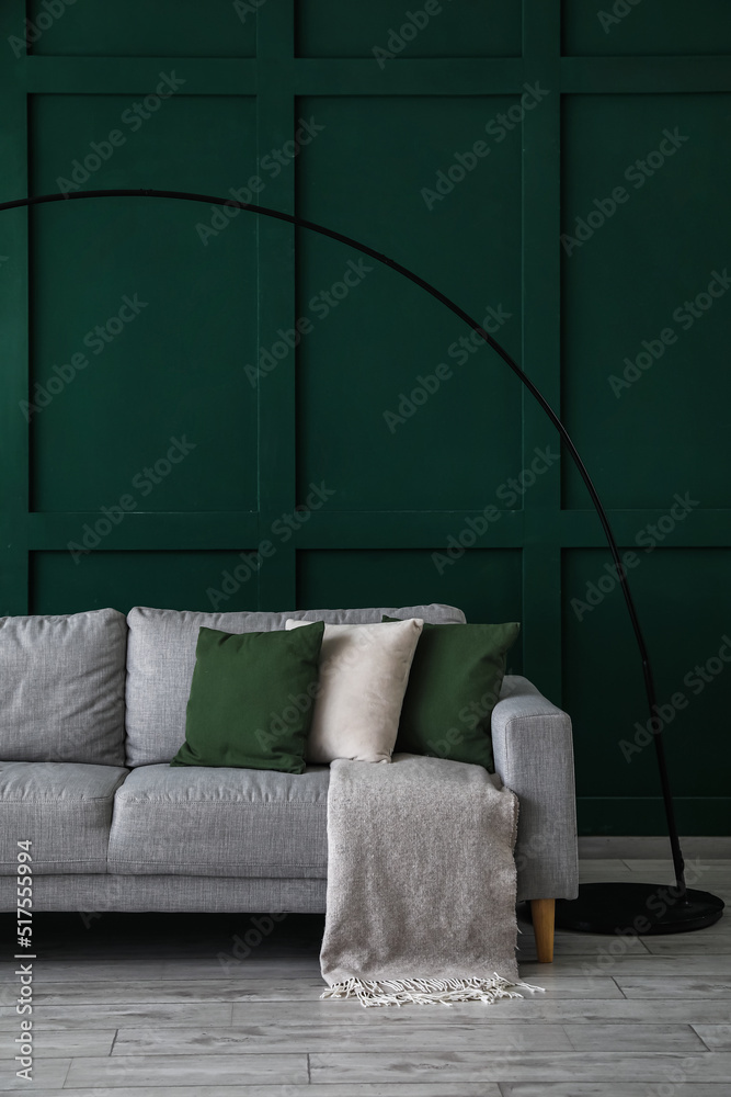 靠近绿色墙壁的带软垫和格子的灰色沙发