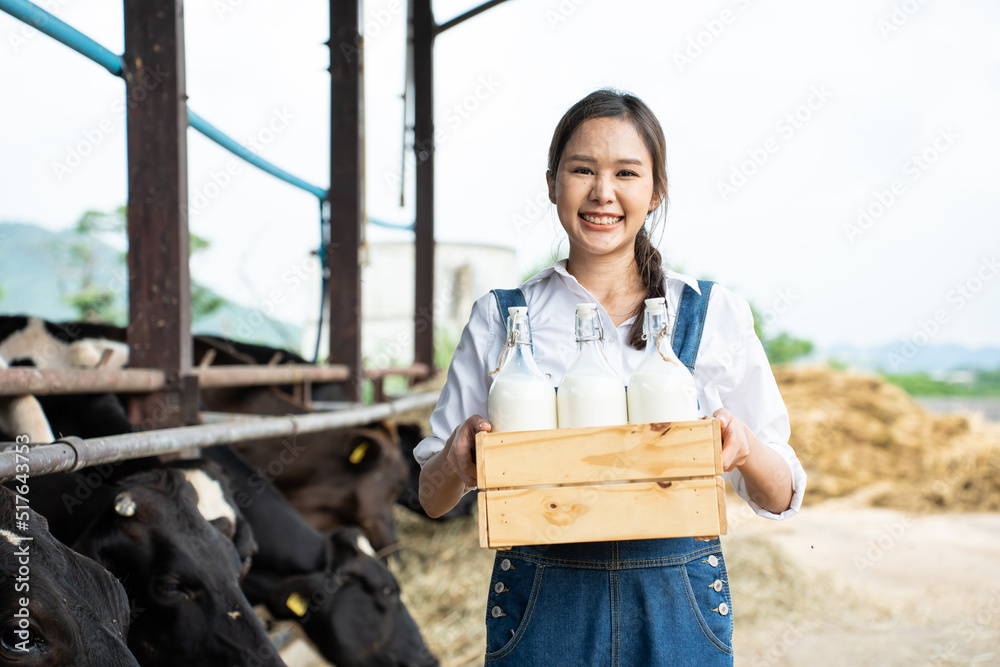 Portrait of Asian woman dairy farmer holding bottle of milk in cowshed