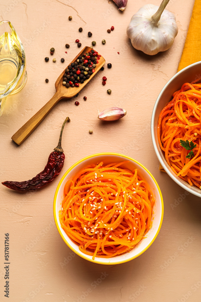 Bowl of korean carrot salad and spices on color background