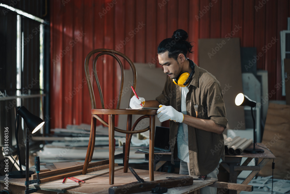 亚洲青年木匠在木工工作台上用卷尺测量椅子