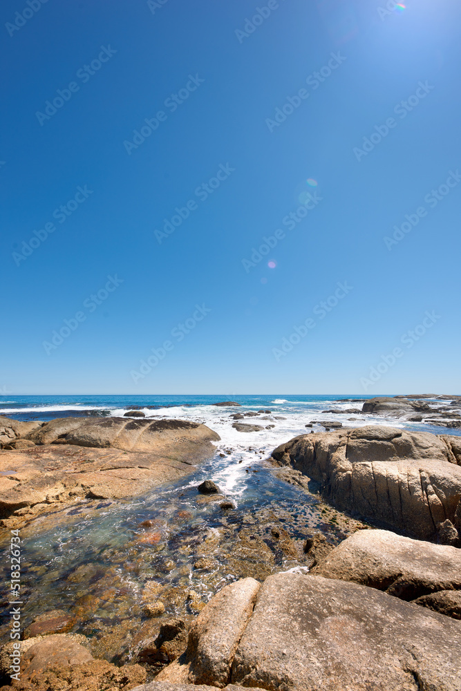 在晴朗的蓝天下，海洋中的大石头有复制空间。美丽的海滩波浪景观，t