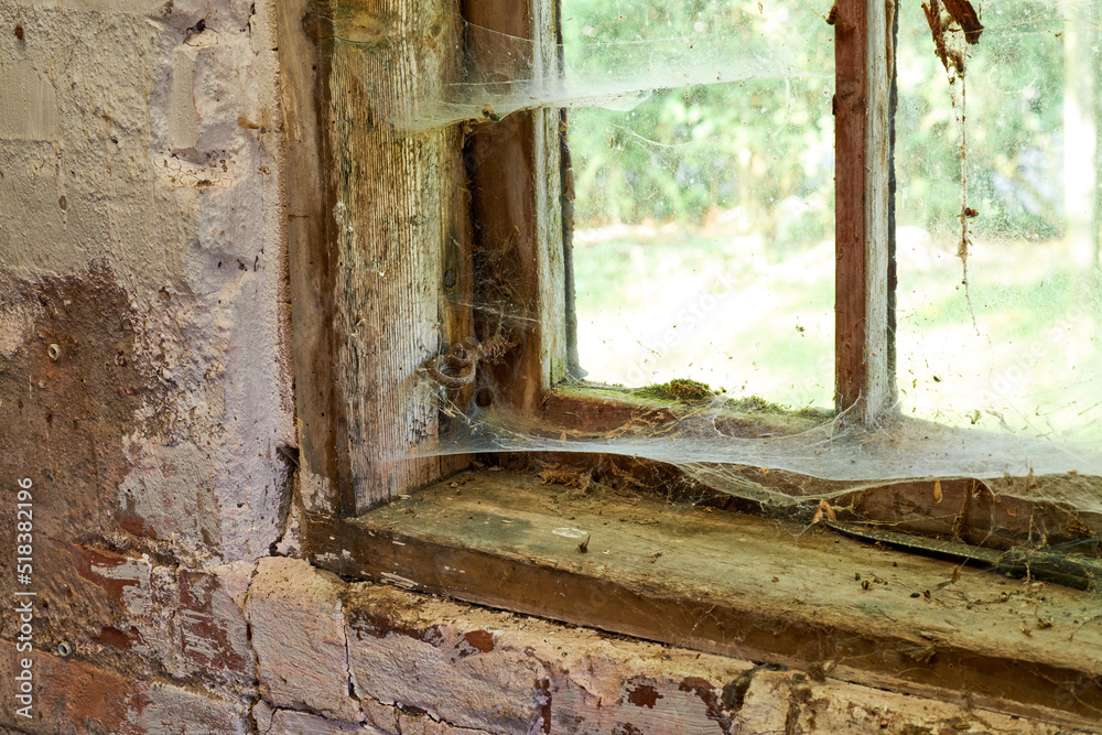 需要TLC的古房子的内部视图。一扇旧窗户，窗户上有灰尘和蜘蛛网