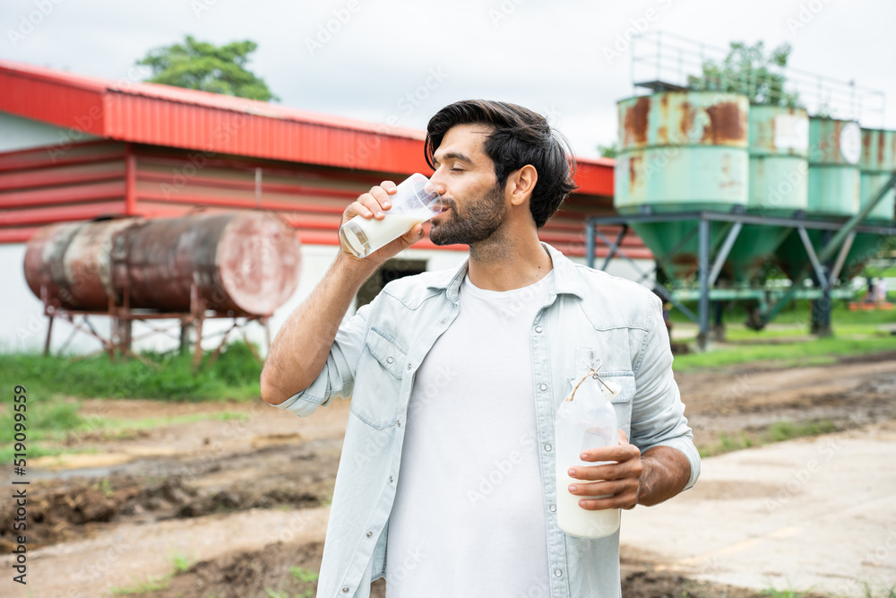 Portrait of Caucasian man dairy farmer drink bottle of milk in cowshed