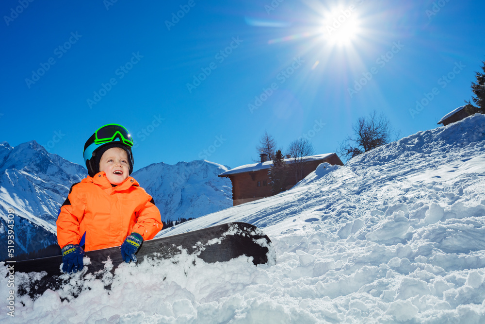 高山滑雪道上的男孩在山上戴着头盔和口罩坐着