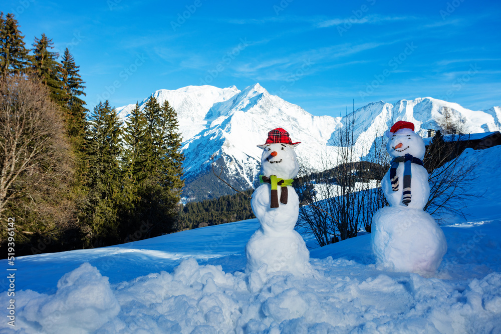 一对雪人在山上戴着胡萝卜帽和围巾