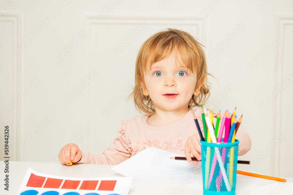 漂亮女孩坐在桌子旁用铅笔画画