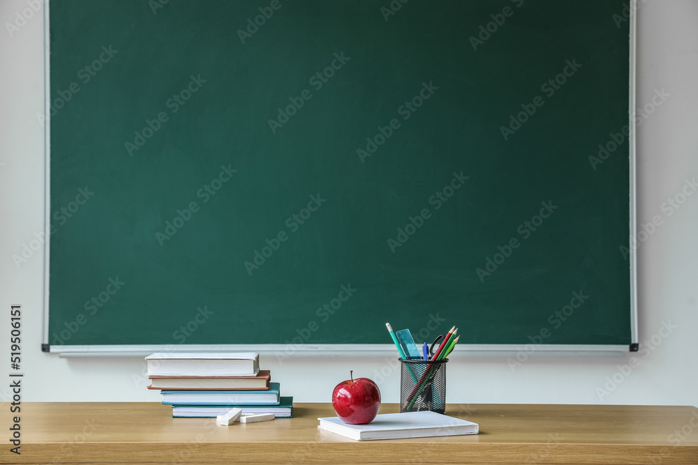 黑板附近桌子上有课本和笔杯的苹果