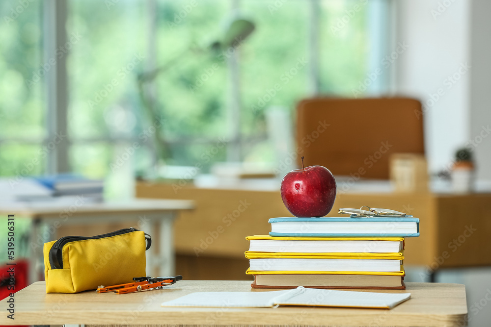 教室桌子上放着课本、眼镜和铅笔盒的苹果