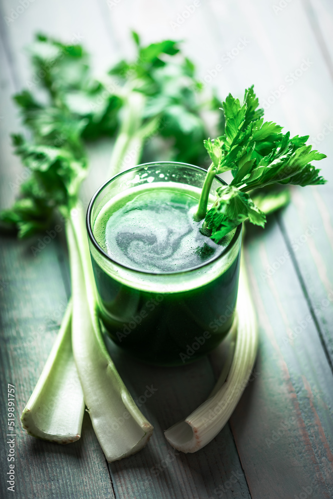 木质背景玻璃中的芹菜鲜绿色果汁。健康素食概念