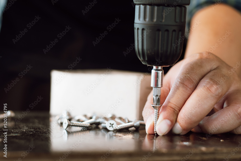 工厂内手持木螺丝电动无绳螺丝刀钻头的男机修工特写