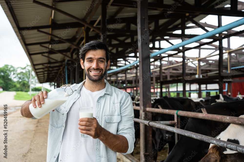 高加索男性奶农在牛棚里拿着一瓶牛奶的肖像