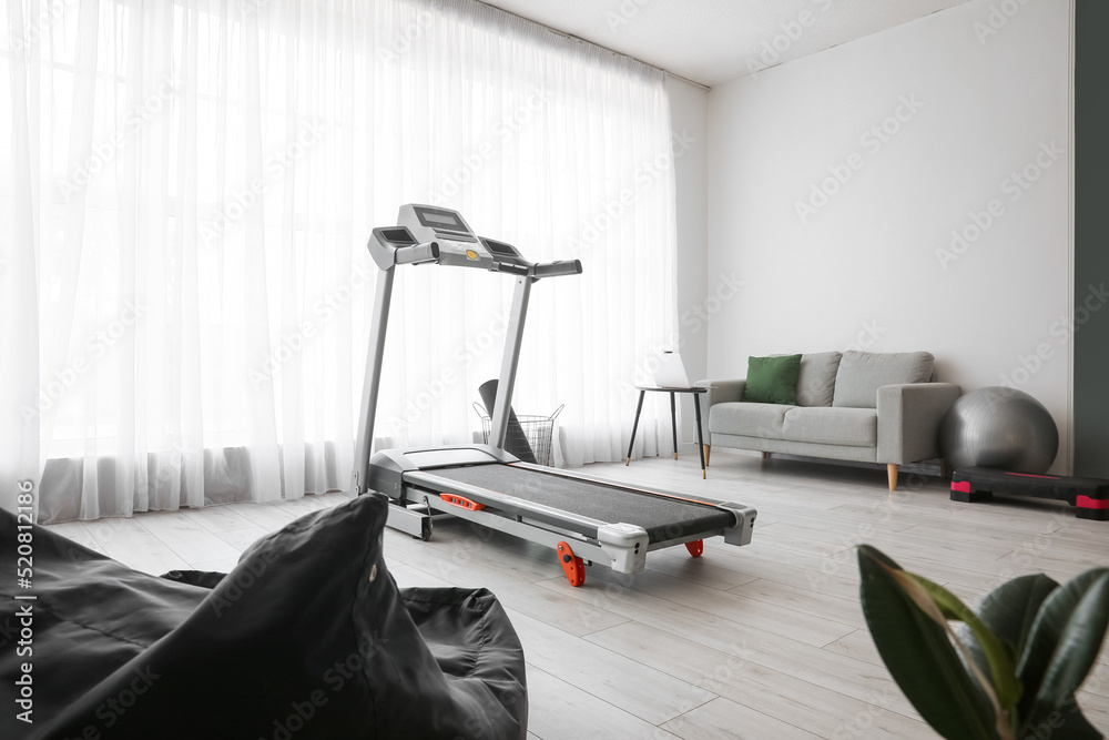 带跑步机、沙发和运动设备的轻型客厅内部