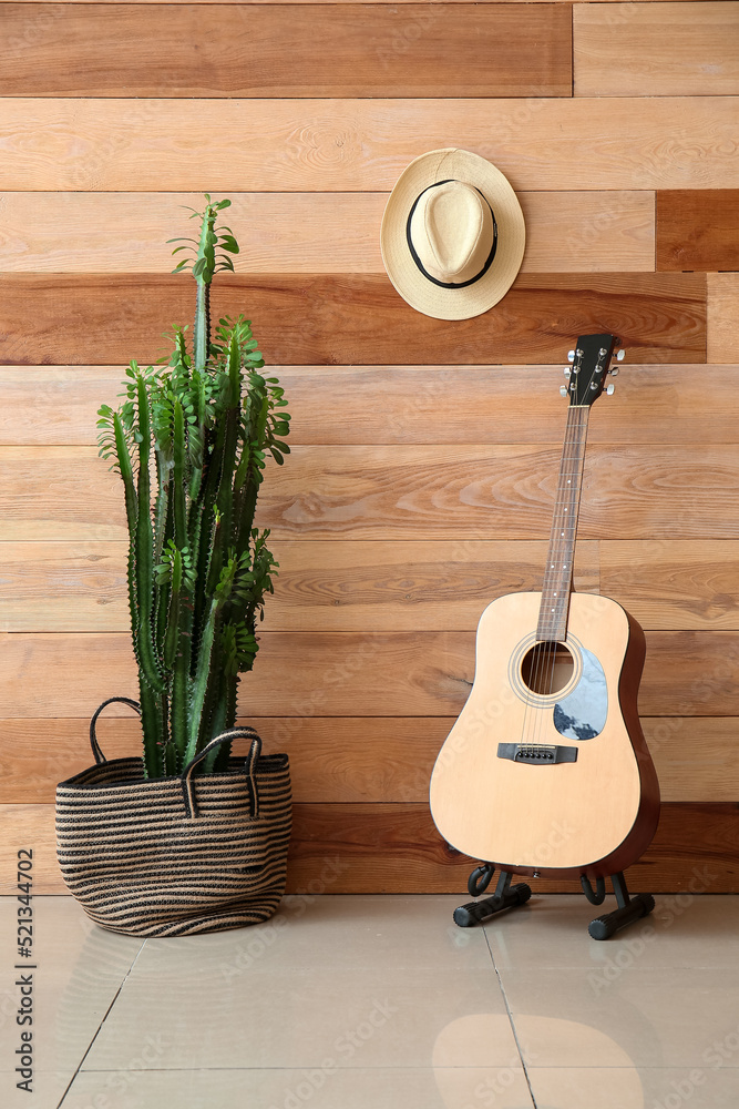 Big cactus, guitar and hat on wooden wall