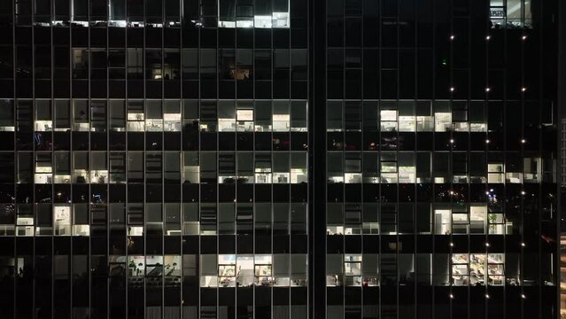 Office buildings with lights in the city downtown. Drone aerial view. People working in office building in the night, building lights in the night .  Economy business cityscape concept b-roll footage.