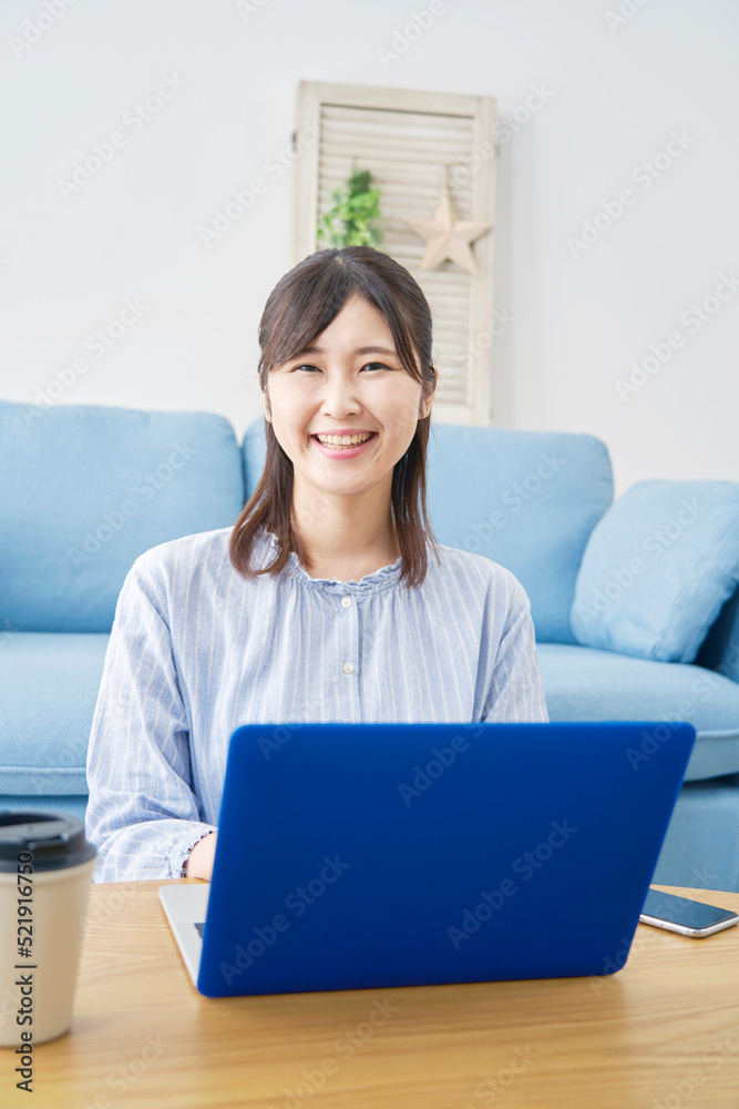 自宅でノートパソコンを使う女性のカメラ目線ポートレート