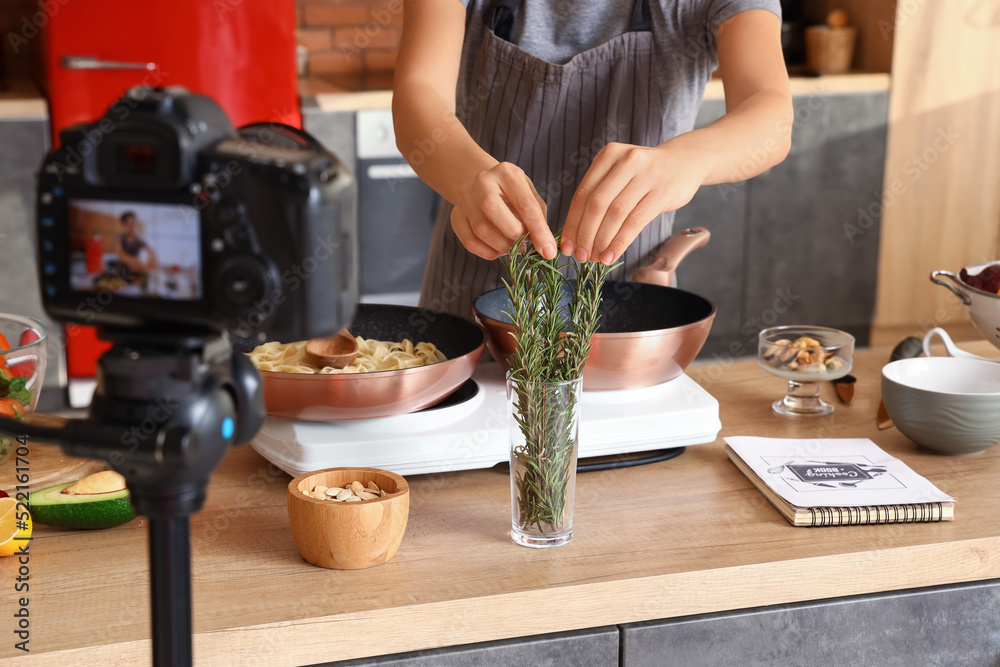 一名年轻女子在厨房录制视频课时服用迷迭香，特写镜头