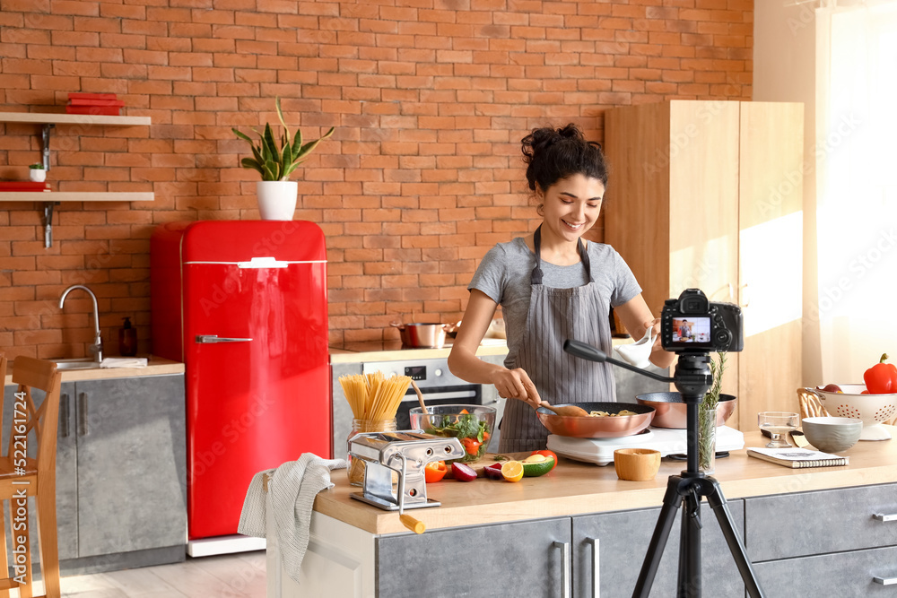 年轻女子在厨房录制烹饪视频课时烹饪意大利面