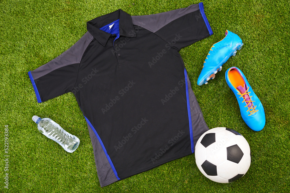 草地背景下运动服或时尚足球服、配饰和设备的平面布置。如上