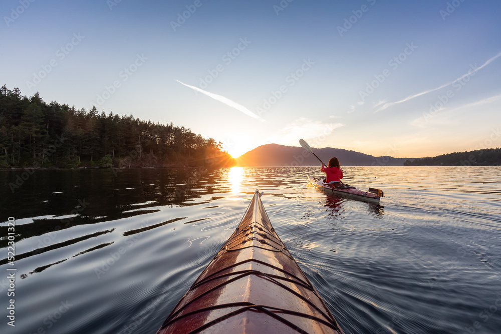 Adventurous Woman on Sea Kayak paddling in the Pacific Ocean. Sunny Summer Sunset. Taken near Victor